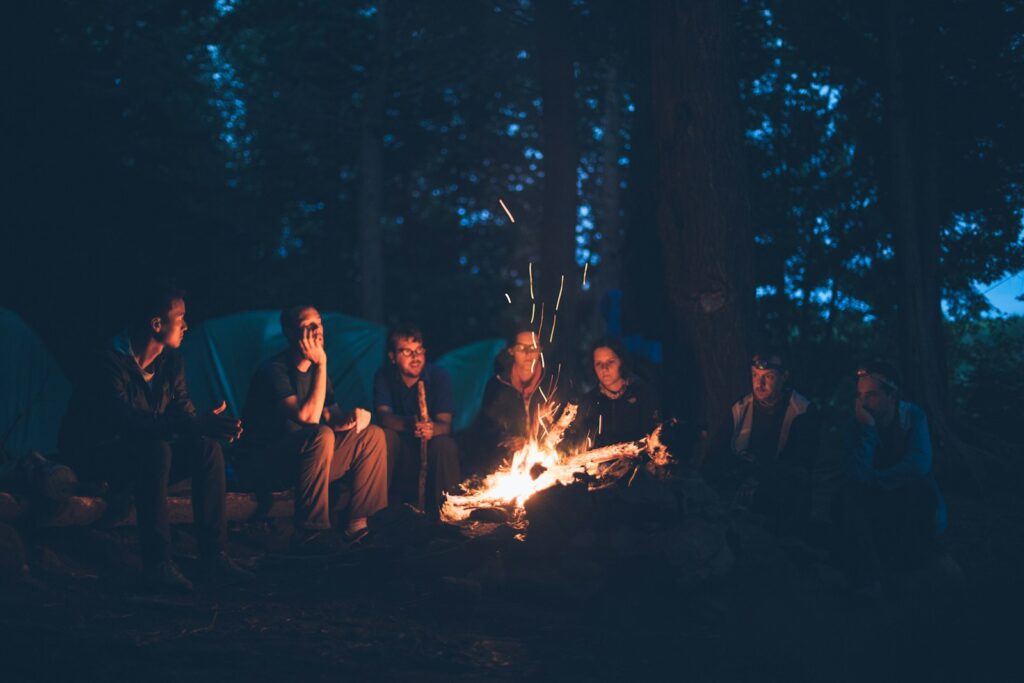 Grupo de scouts alrededor de una hoguera en un campamento en el bosque